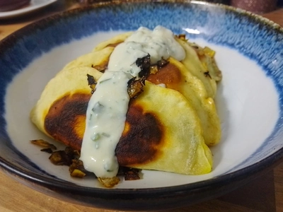 Nahaufnahme von mehreren gebraten Bolani mit Knoblauchtunke und Zwiebel
