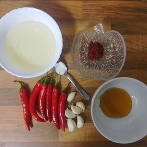 Chilis, Knoblauch, Essig in einer Schale, Salz auf einem Teelöffel, Tomatenmark und Honigersatz auf einer Küchenarbeitsplatte