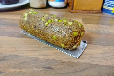 Gebackene Seitan-Hafer Wurst mit Erbsensplitter welch auf der restlichen Alufolie ruht